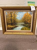 Full view of the framed landscape painting showing river and trees in autumn colors.