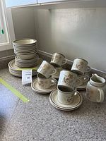 Full view of stacked plates, bowls, cups, saucers and milk jug on counter