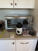 Black+Decker combo air fryer, convection oven, and toaster appliance on kitchen counter with Starfrit personal blender with cups and lids beside it