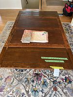 Full view of vintage oak barley twist table with leaf and assorted table linens on top, placed on floral patterned rug.