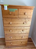 Front view of solid pine tall boy dresser showing 6 drawers with round wooden knobs.