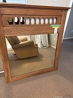 Front view of the solid oak framed mirror showing decorative cutouts at the top and clear mirror surface below.