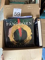 Box containing three hardcover books with titles visible