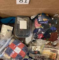 Overview of box showing quilt squares, storage box, bags of findings and fabric scraps