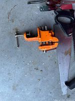 Bench vise, screwdrivers and hand saw visible on garage floor