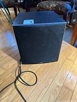 Front view of Polk Audio PSW504 powered subwoofer with grille and attached power cord