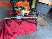 Chainsaw with spare bar and chains on red cloth
