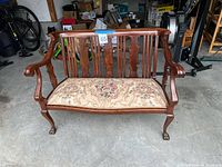Front view of wooden loveseat with floral seat