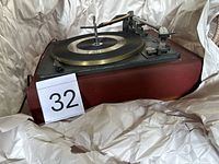 Side view of Garrard AT6 turntable in packing paper, shows wooden plinth and platter