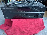 Front view of Yamaha RX-V473 receiver on red cloth with remote on top