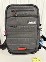 Front view showing OGIO logo, grey patterned fabric, red zipper pulls
