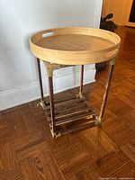 Photo of the side table showing round wooden tray top, metal brackets on legs, and slatted shelf