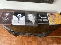 Photo of all five books on a wooden table including the three from the lot and two additional ones not listed in the description.