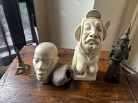 Five assorted figurines/statues on a wooden surface, showing the mix of materials and styles.