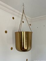 Full view of hanging planter on wall showing shape, finish, and chain