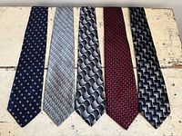 Group of five neckties laid flat side by side displaying patterns