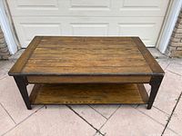 Full view of rectangular wood and metal coffee table against garage backdrop