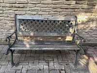 Full view of rustic wood and metal outdoor bench against brick wall
