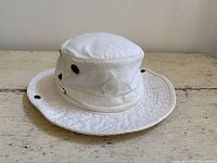 Profile view of off-white Tilley bucket hat showing brim, crown, and eyelets