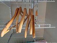 Seven wooden hangers on wire shelf including six contoured and one clip style