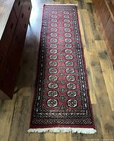 Full view of the red hand-woven runner rug on wooden floor