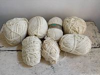 Seven ivory acrylic yarn balls displayed on tabletop