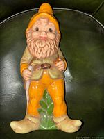 Full view of ceramic gnome seated with walking stick