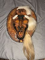 Full front view of carved mask on plaque