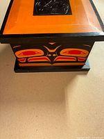 three-quarter view of box showing painted eagle motif and orange top