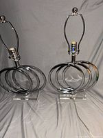Both chrome ring table lamps front view showing ring design, bases, harps, finials, and cords
