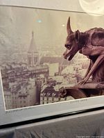 Overall view of framed signed photograph featuring gargoyle and city backdrop