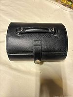 Top view of black leather handbag showing handle and snap tab