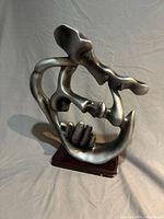 Front view of abstract kissing couple sculpture on wood base