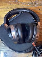 Headphones resting on carry case showing earcups, cable and bronze accents
