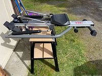 Rowing machine folded on a stand, full side view shows frame, arms, seat, footrests