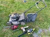 Overall view of lawn mower and three chainsaws on grass
