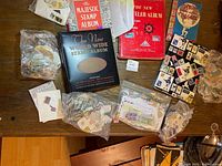 Overhead view of four stamp albums, Stamp Finder booklet and multiple bags of loose stamps