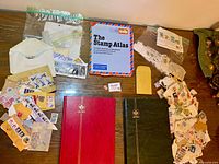 Overview showing two stockbooks, Stamp Atlas book, loose stamps in envelopes and bags