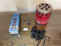 All items grouped: boxed walkie-talkie, small stove, red heater, binoculars