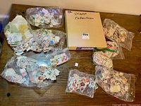 Album and seven bags of loose stamps on table