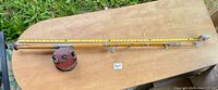 Full view of rod with reel attached beside measuring tape