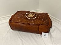 Overall view of brown embroidered leather pouf