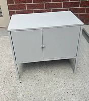 Front view of light grey metal cabinet showing two doors and knob handle