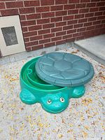 Sandbox with lid set askew showing turtle form