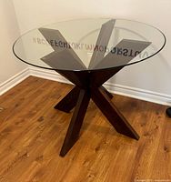 Full view of table showing glass top and X-shaped wood base