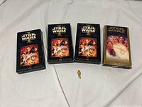 Front view of three Phantom Menace VHS tapes, one Star Wars Special Edition VHS and gold C-3PO figure