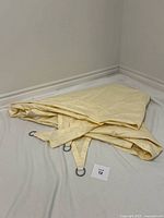 Folded beige triangle shade sail showing D-rings and stitched fabric