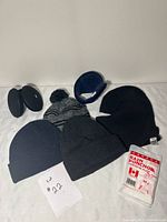 Group shot of all hats, earmuffs, balaclava and packaged poncho