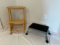 Wooden two-step stool and grey metal folding stool side by side
