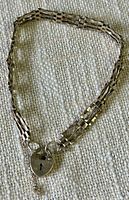 Full image of the silver bracelet laid out, showing the linked structure and heart-shaped clasp with keyhole.